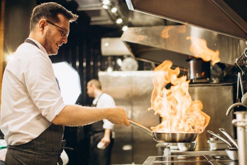 Chef frying meat, commercial kitchen, high heat cooking, professional frying, kitchen safety, commercial catering